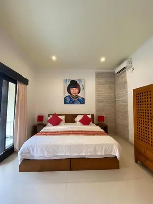 a bedroom with a large bed with red pillows at Sirkus Guesthouse in Canggu