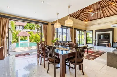 a dining room with a table and chairs and a pool at Aileen 4 BR Private Pool Villa in Seminyak