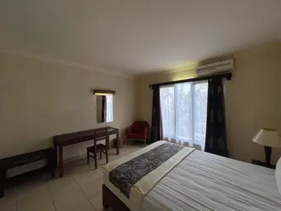 a bedroom with a bed and a desk and a window at Puri Samaritan in Denpasar