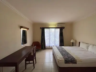 a bedroom with a bed and a desk and a window at Puri Samaritan in Denpasar
