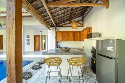 a kitchen with a refrigerator and two bar stools at Tuluscoliving Villa Legian 4 Bedrooms and 4 Bathroom in Legian