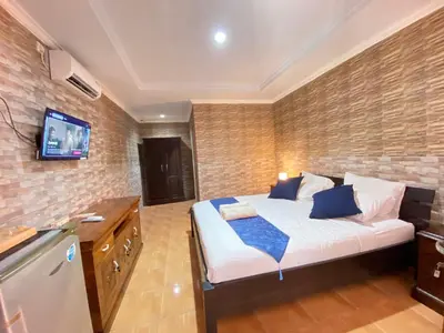 a bedroom with a bed and a tv on a brick wall at ABI Hotel3 - 1 minute to the Beach and 1 second to the Mall in Ngurah Rai International Airport