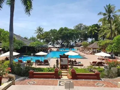 a pool with chairs and umbrellas in a resort at Apartemen 6236 at Jayakarta Residence Bali in Seminyak