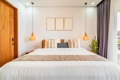 a bedroom with a large white bed with pendant lights at Bimala 3 BR Private Pool Villa in Seminyak