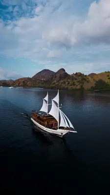 a boat with three sails in the water at Boat Komodo in Seminyak