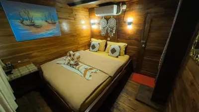 a small bed in a room with wooden walls at Boat Komodo in Seminyak