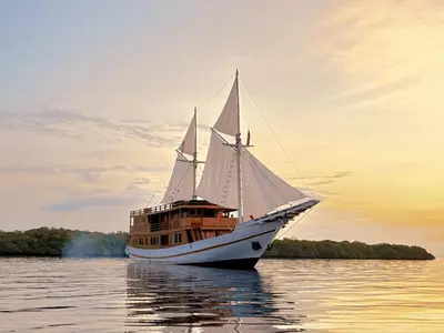a boat in the water with a sunset in the background at Boat Komodo in Seminyak