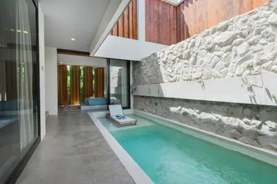 a swimming pool in a house with a stone wall at Shankara 2 BR Private Pool Villa in Seminyak