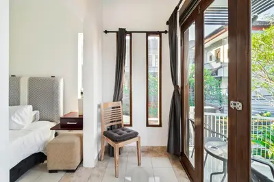 a bedroom with a bed and a chair and a balcony at Balinese Home with Pool near Padma Beach, Legian in Legian