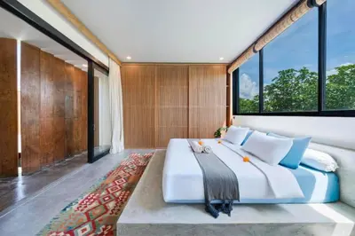 a bedroom with a large bed and large windows at Quilon 2 BR Private Pool Villa in Seminyak