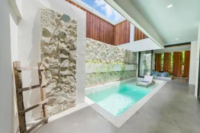 an indoor pool in a house with a stone wall at Quilon 2 BR Private Pool Villa in Seminyak