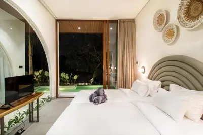 a bedroom with a white bed and a large window at Villa Lalalax 3BR Tropical Retreat in Jimbaran in Uluwatu