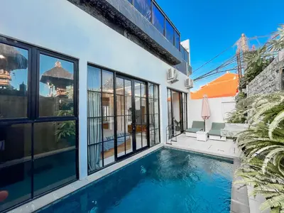 a swimming pool in a house with windows at Villa Diah in Seminyak