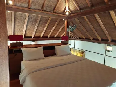 a bedroom with a large white bed with two lamps at Bumahan Villa in Seminyak