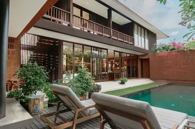 a house with a swimming pool and two chairs at Bali Radiance 4 bedrooms with private bathrooms - Pool, Beach & Airport in Ngurah Rai International Airport