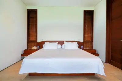a bedroom with a large white bed with two windows at Bali Radiance 4 bedrooms with private bathrooms - Pool, Beach & Airport in Ngurah Rai International Airport