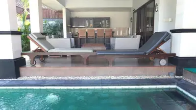 a pool with two lounge chairs next to a house at Tahoma Villas Seminyak by ABM in Seminyak