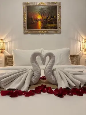 two swans are laying on a bed with red roses at Casa Benoa Homestay in Nusa Dua