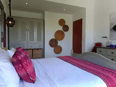a bedroom with a white bed with a pink pillow on it at Tropikal villa 2 bedrooms in seminyak Bali in Seminyak
