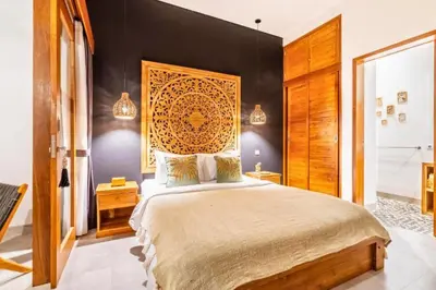 a bedroom with a large bed with a wooden headboard at Avery 1 BR Private Pool Villa in Seminyak