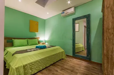 a green bedroom with a bed and a mirror at Villa Odil, Great Value 700m beach & 15m pool in Seminyak