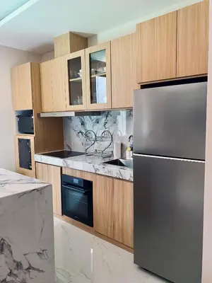 a kitchen with a stainless steel refrigerator and wooden cabinets at Villa Bun Blessi in Pesanggaran