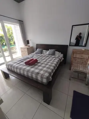 a bedroom with a bed with a red pillow on it at Kubusawah Guest House in Seminyak