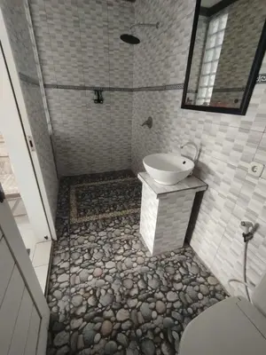a bathroom with a shower with a sink and a toilet at Kubusawah Guest House in Seminyak
