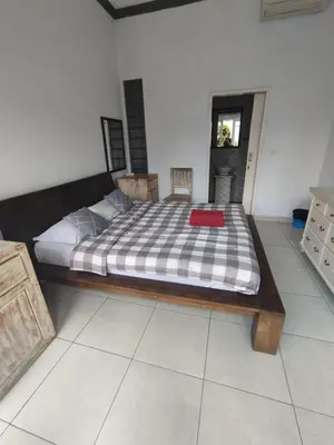 a bedroom with a large bed with a wooden frame at Kubusawah Guest House in Seminyak