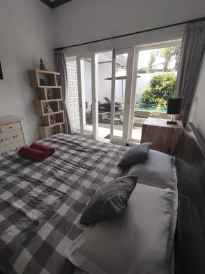 a bedroom with a bed with pillows and a window at Kubusawah Guest House in Seminyak