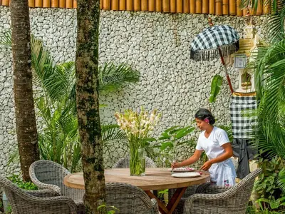 a woman sitting at a table in a garden at Villa Lulito in Seminyak