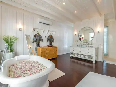 a white bathroom with a tub and a mirror at Villa Lulito in Seminyak
