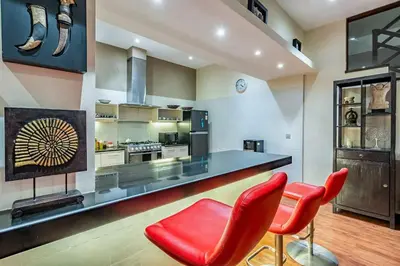 a kitchen with two red chairs and a counter at Panatai Villa in Sanur