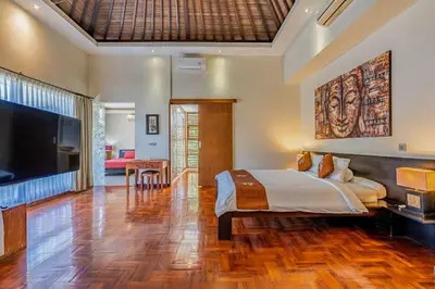 a bedroom with a large bed and a flat screen tv at Panatai Villa in Sanur