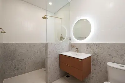 a bathroom with a sink and a toilet and a mirror at Alegria De La Casa Seminyak in Seminyak