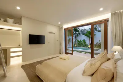 a bedroom with a large bed and a television at Alegria De La Casa Seminyak in Seminyak