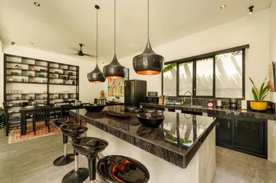 a kitchen with a large island with black counter tops at Elegant Modern 4BR Retreat in the Heart of Berawa in Canggu