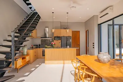 a kitchen and dining room with a table and a staircase at Luxury 4BR Villa Private Pool & Sea Horizon in Kerobokan