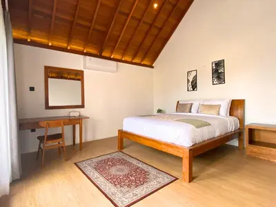 a bedroom with a bed and a table and a mirror at De Awan Villa in Kerobokan