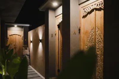 a row of wooden doors in a hallway at Dikubu Belong in Seminyak