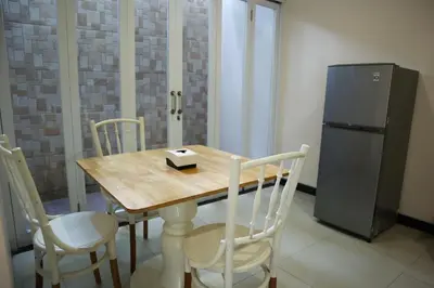 a kitchen with a wooden table with chairs and a refrigerator at Sunrise Aventus Villa Nusa Dua in Nusa Dua