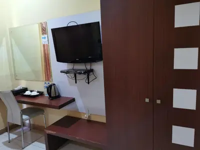 a room with a desk and a television on a wall at Mutiara Mansion Aparthotel in Seminyak