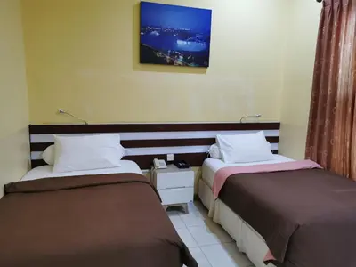 a hotel room with two beds and a tv at Mutiara Mansion Aparthotel in Seminyak