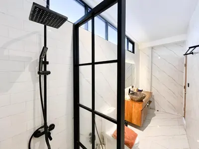 a glass shower door in a bathroom with a sink at Villa Arti in Seminyak