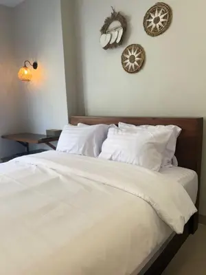 a bedroom with a bed with white sheets and pillows at Flamboyant Guesthouse in Seminyak