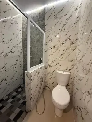a bathroom with a white toilet and a window at Flamboyant Guesthouse in Seminyak
