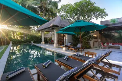 a swimming pool with chairs and umbrellas at 4-Bedroom Villa - Large swimming pool - Ideal place for friends and families in Seminyak