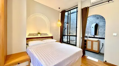 a bedroom with a white bed and a large window at Villa Lans By Baliem Villa in Jimbaran