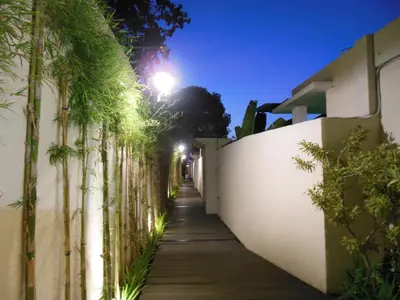 an alley with a white fence and palm trees at HK Villa Bali in Legian