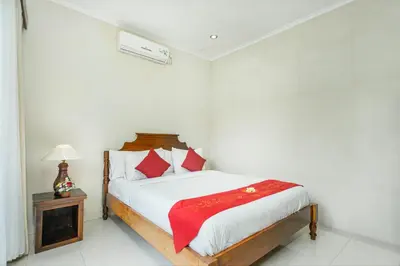 a white bedroom with a bed with red pillows at Abimanyu Villa 2 Seminyak in Seminyak